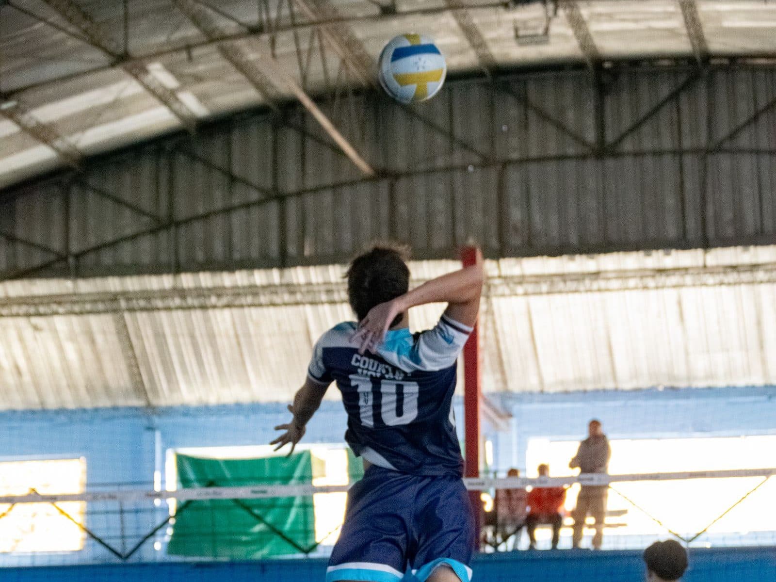 A youth volleyball player jumping to play the ball at the net